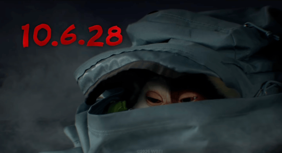 A close-up of a small creature peeking out from an unzipped gray jacket, with the date '10.6.28' in bold red lettering in the background.